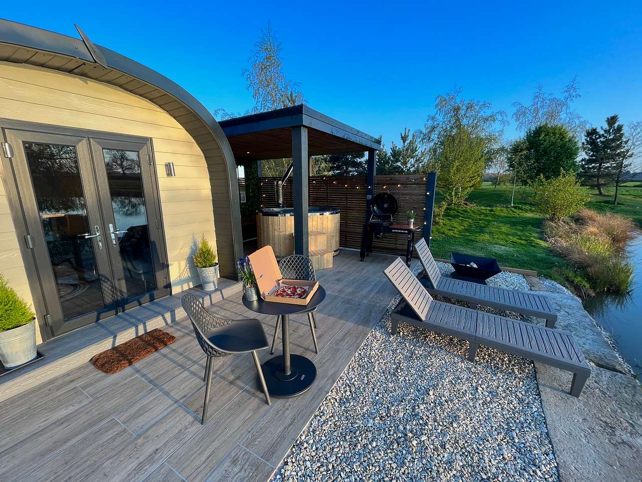Your spectacular outdoor area consists of wood-fired hot tub, fire pit, BBQ, sun-loungers, table & chairs, fish from your your pod, lakeside & beautiful sunset views, pizzas can also be delivered to the site. 