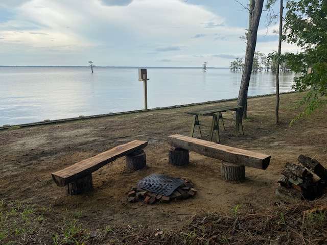 Campsite #3.  At all sites you can pitch a tent at the edge of the water (next to the bulkhead).  Differences at site 3: The fire pit the closest to the water. But, you cannot park your vehicle next to it. Your vehicle is very close (~12 feet), but you have to walk up an incline to the 'upper level'.