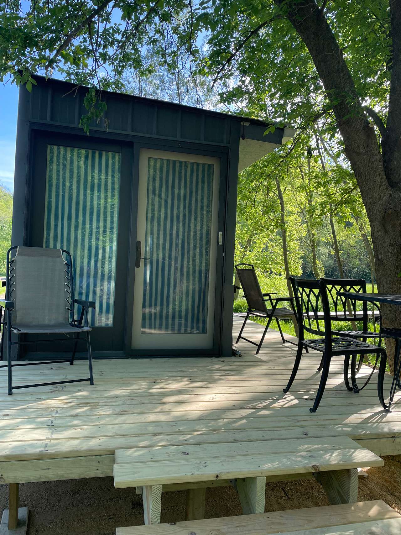 Front deck with view of the woods and creek,  and dining table and chairs. 