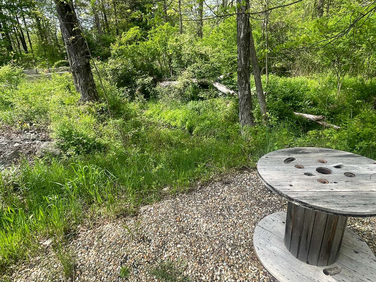 Small gravel area with 3’ spool table overlooking creek