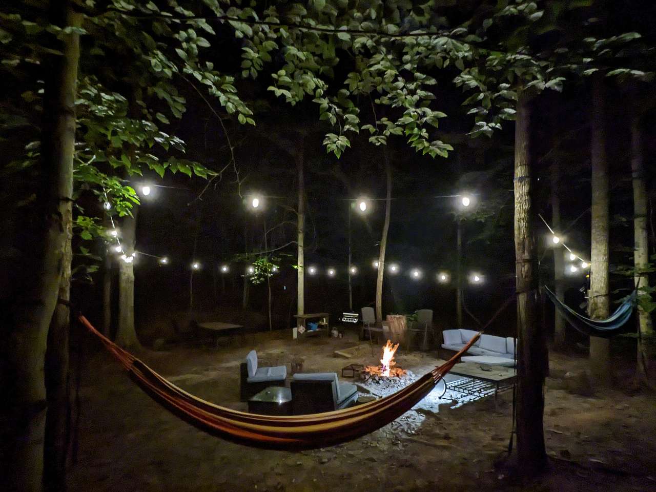 Dining table, grill, and kitchen area in the background, right next to the creek