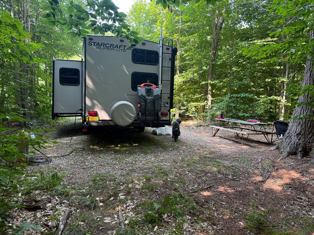 From rear of pad. Power and water to the left rear corner. Behind me is a path down to the “White Trail” which loops the lake. And you can see the lake. 