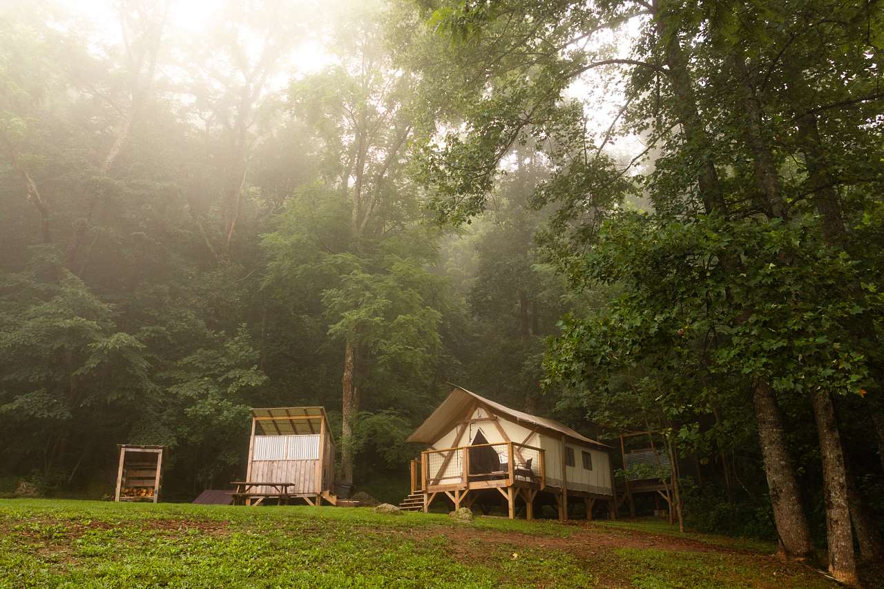 The Bella tent with the outdoor kitchen and fire woods to the left and a full bathhouse to the right