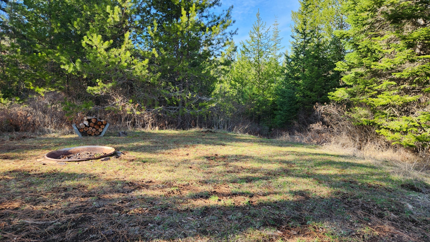 Tent side near fire pit and wood supply.