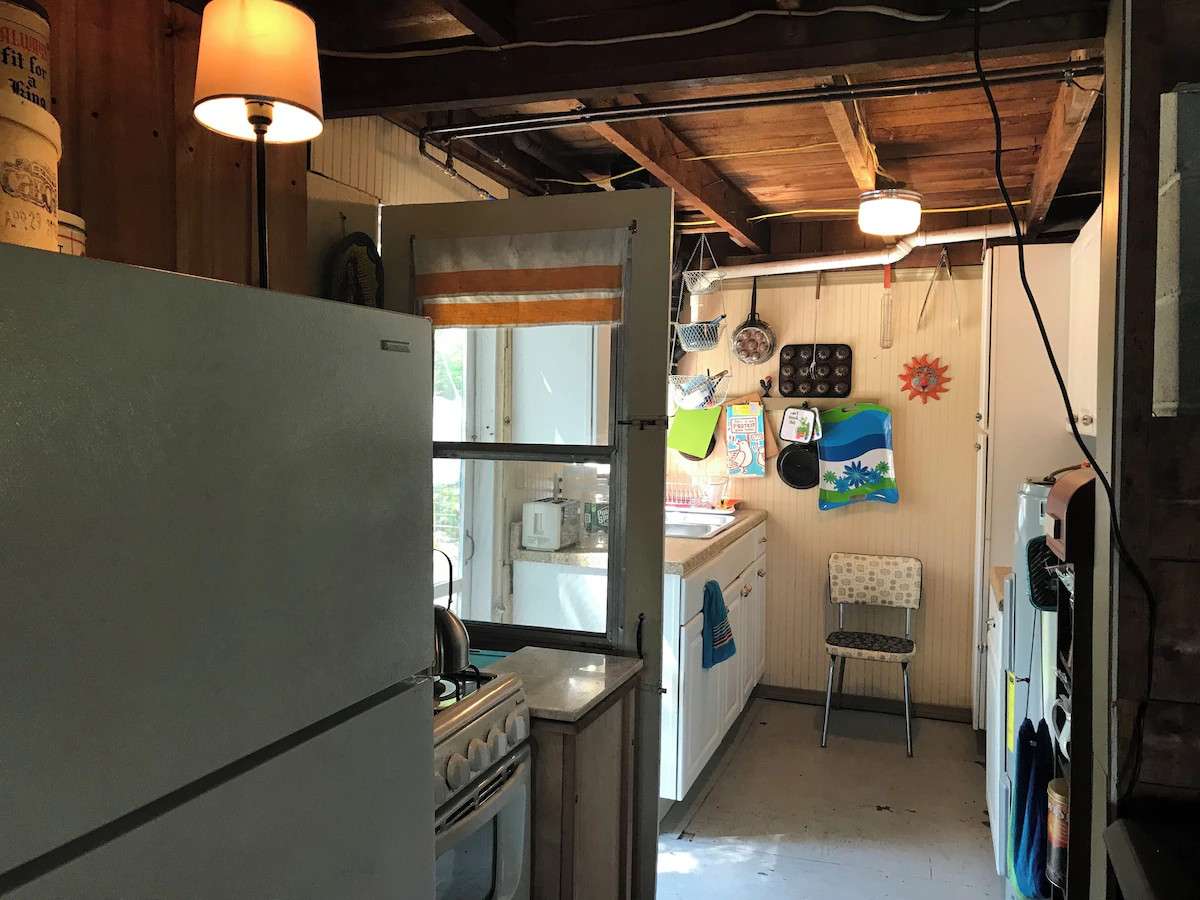 Fully equipped galley kitchen: the appliances include a propane gas range, full-size fridge with freezer compartment, large microwave and large toaster oven, coffee maker and tea kettle. The kitchen door goes out to a small deck with clothesline.