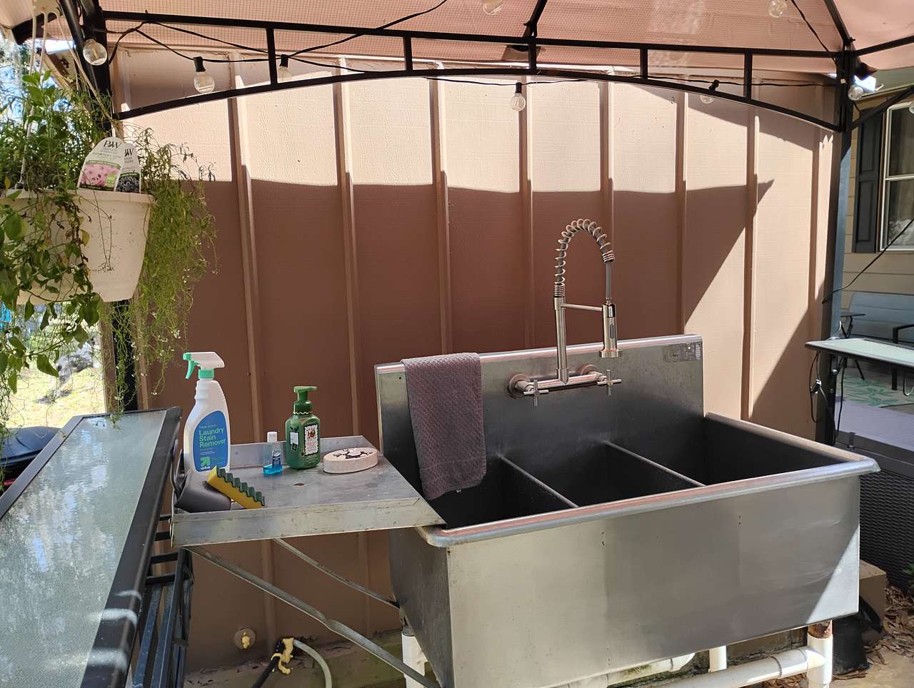 Outdoor sink with Spray Faucet and 4 gallon hot water heater located under lighted gazebo cover.