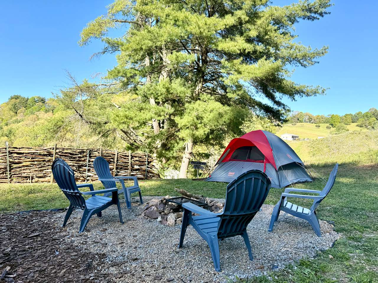 Fire pit with tent site in the background. Chairs included, and tent is not