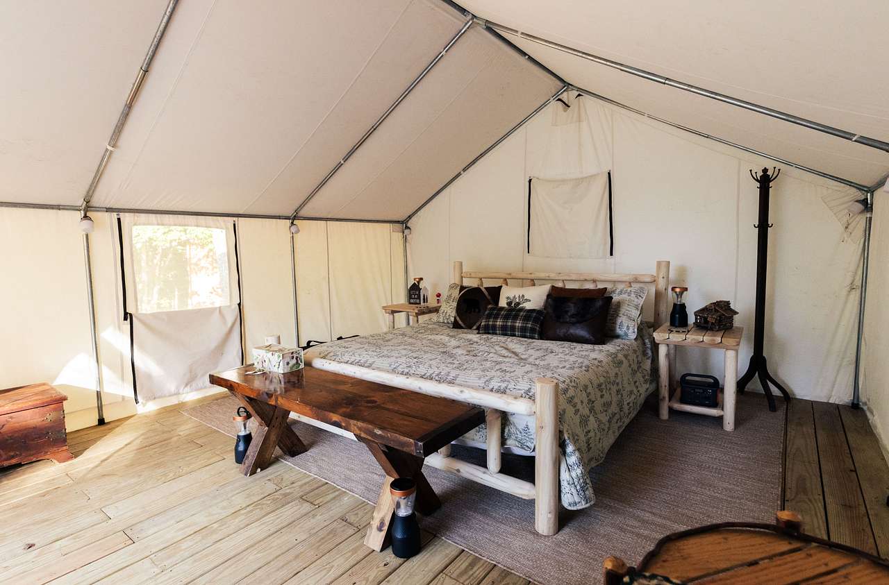 King sized bed inside the tent, with added seating, chairs, and jackery charging station