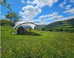 Tent pitches are 5m x 7m levelled grass pitches, chosen on arrival by guests. Access is on foot only and distance from carparks is between 30m and 250m up a gentle slope depending on choice. Wheenbarrows are provided to move kit. Views are stunning of the valley below :)