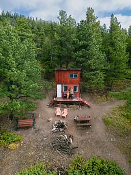 View of the cabin, fire pit. swing and chairs