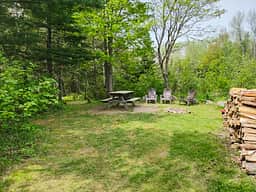 Site entrance with firepit, picnic table, chairs, and wood.
Out of picture, to the left, is the port-a-potty, trash bin, and more space to put a tent