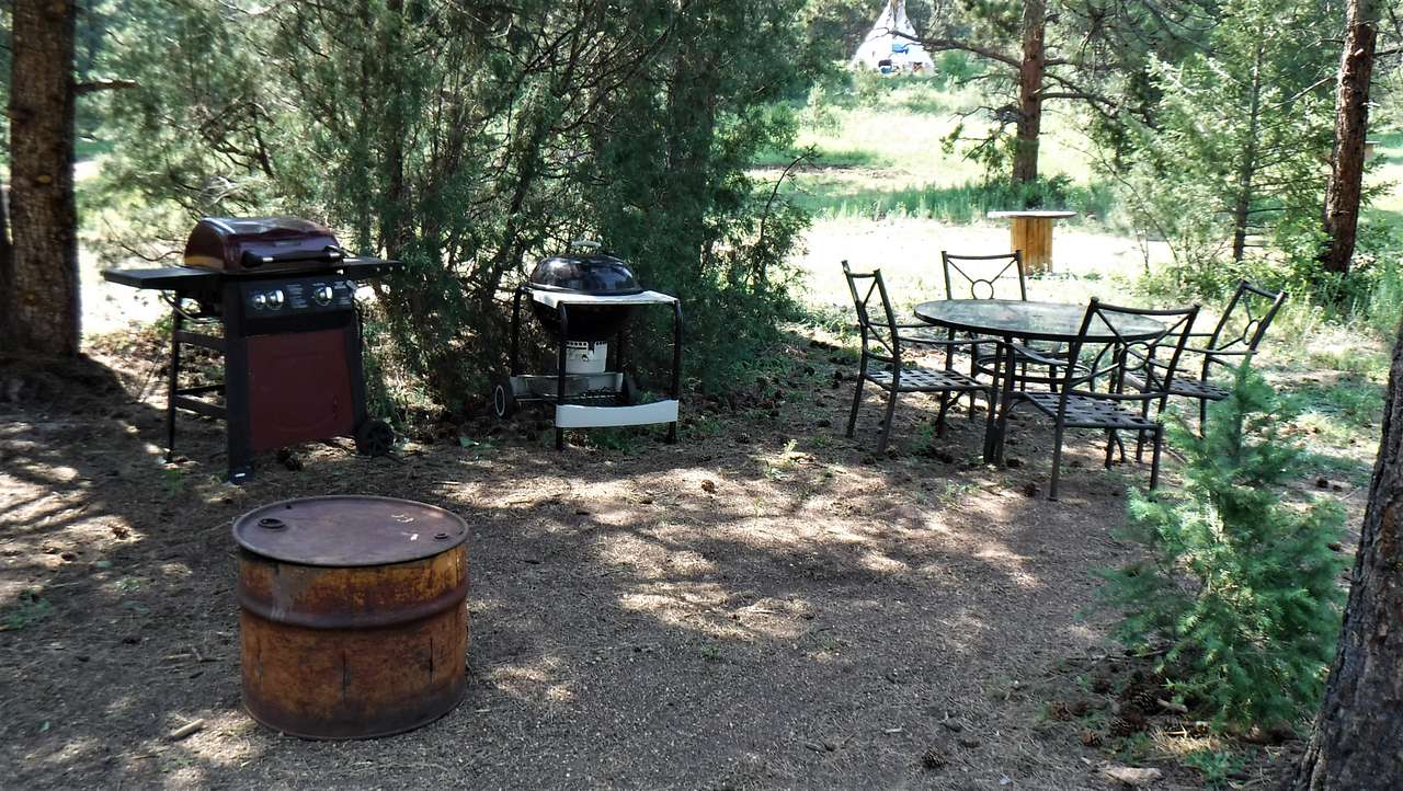 Pony Roundup campsite amenities include: a charcoal grill; a fire pit barrel; patio table and chairs; and large bar height spool table.