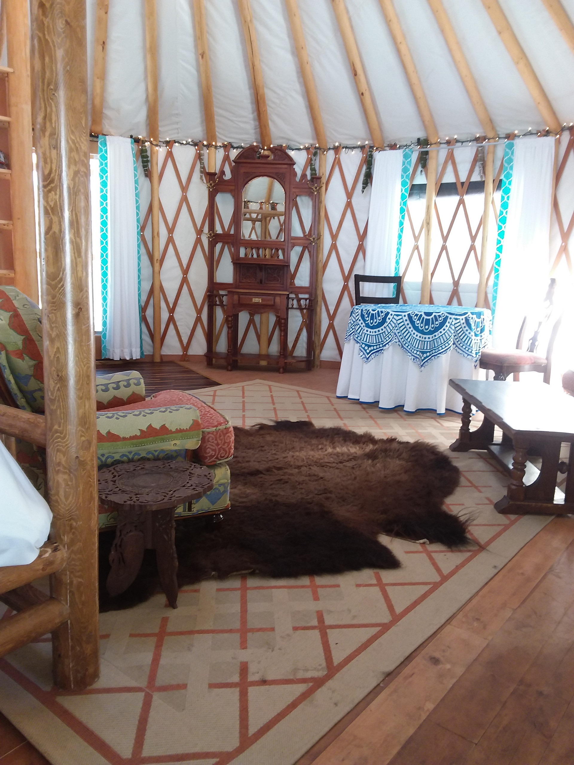 Interior Yurt, complete with comfy king size bed (and bedding), couch, table and chairs, bookcase and wood stove, 