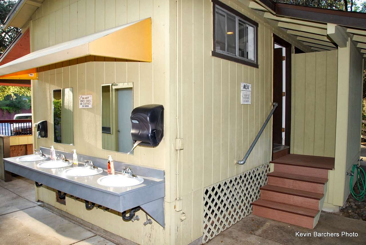 The communal bathroom building has two separate rooms for men and women, each with two toilet stalls and two shower stalls. Sinks are located outside. 