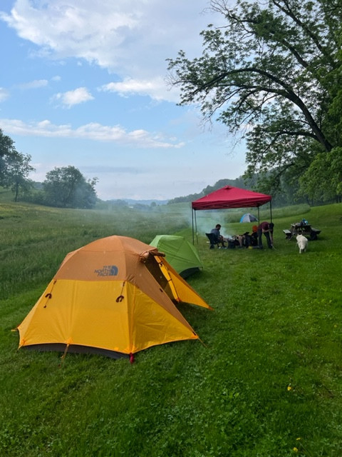 Campsite #1 - three campers enjoying shelter while it rains. There are 3 separate tents. Two in the foreground and one behind the red shelter. 