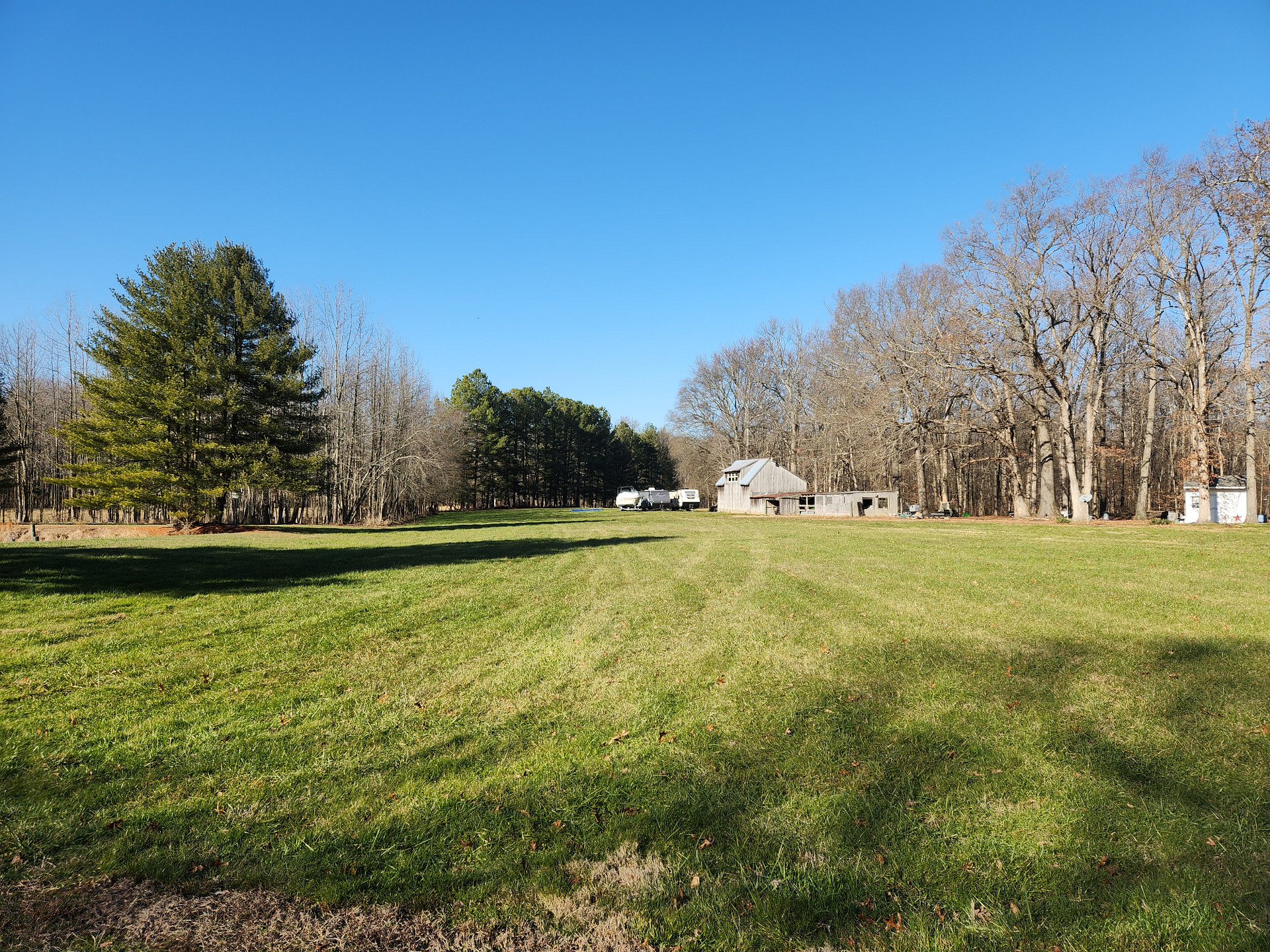 Photo from the driveway towards the back of the property. There are two campers and boat being stored here.
