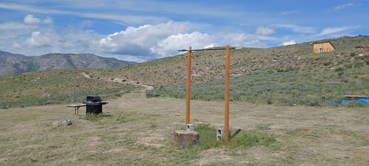 View of the campsite with the propane grill, table and a rack you can hang whatever you want! An outdoor shower, clothes, or the days hunt. 