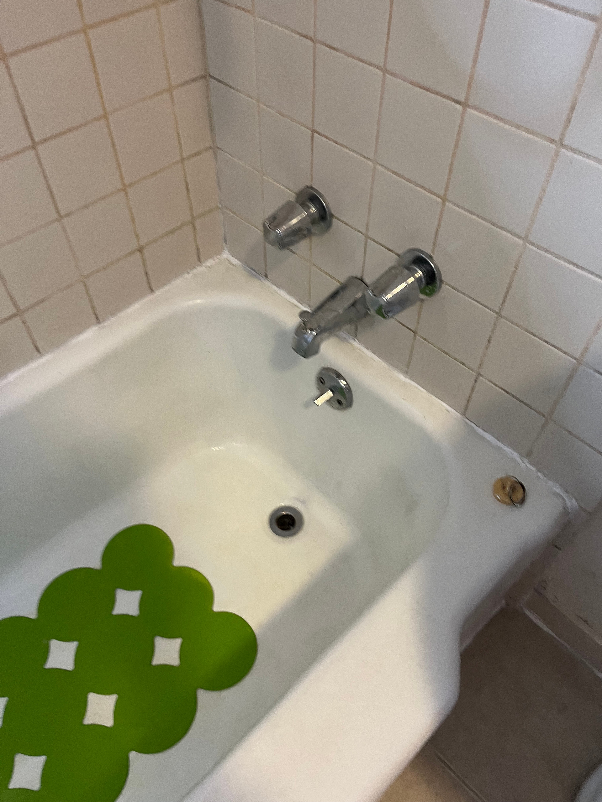 Bathtub surrounded by tiles which have been scrubbed with an electric brush, and Bathtub with fresh sealant. 