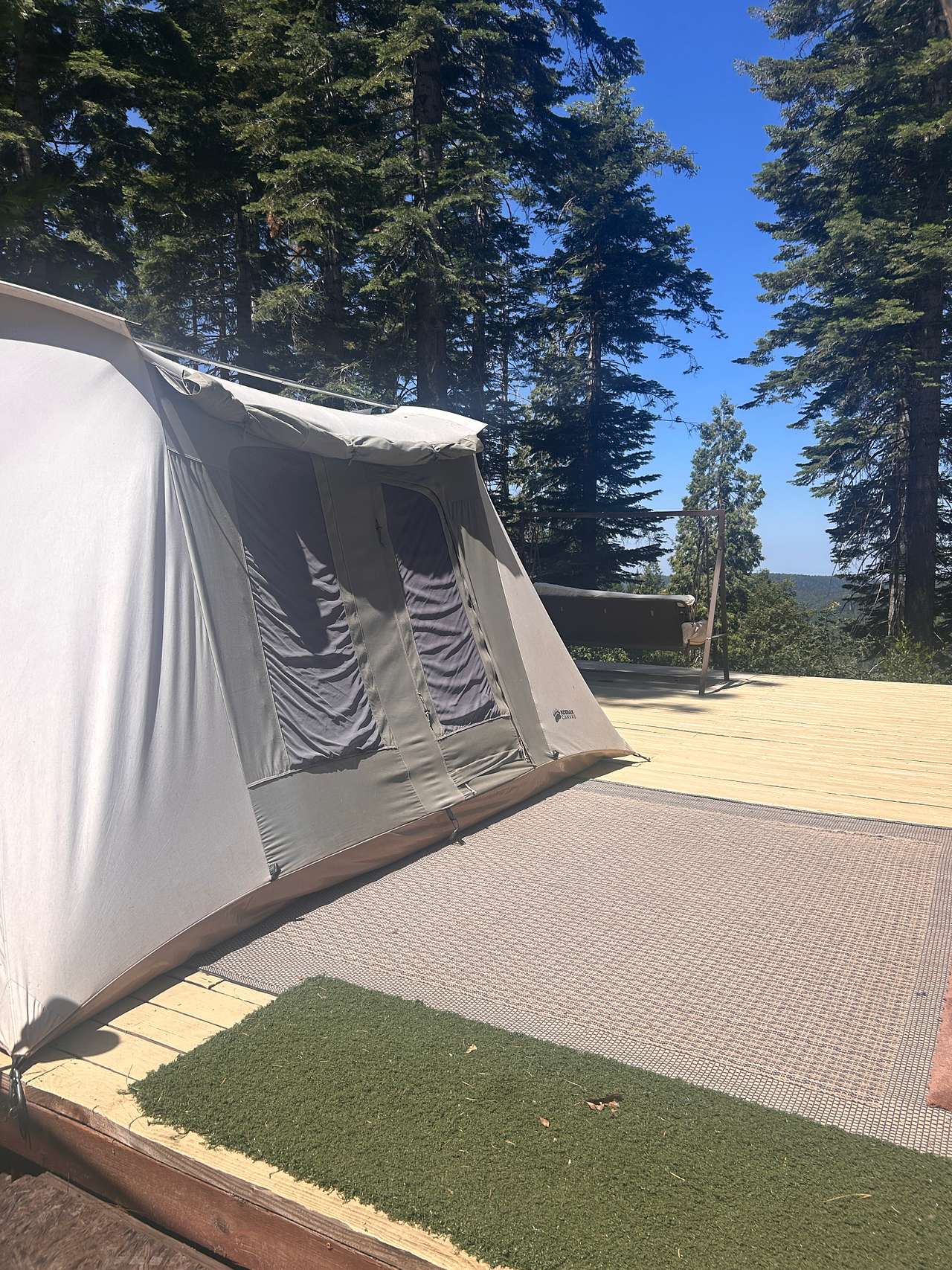 10x14 Kodiak Tent with a queen bed, nightstand, and cot. Located on the corner of the deck, adjacent to the communal kitchen. 