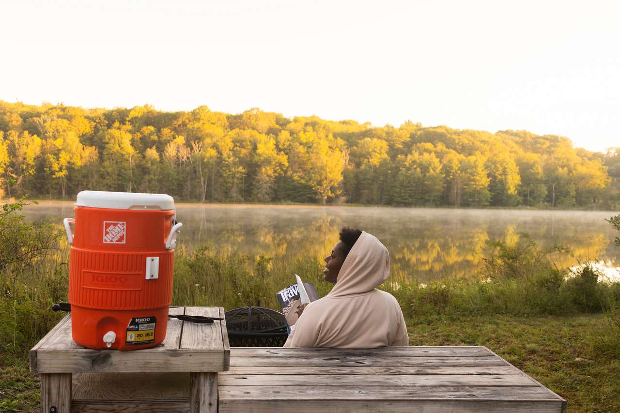 Reading a magazine as the sun rises on the picnic table just outside of our tent