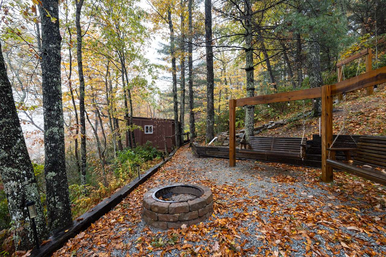 Fire pit area with swinging benches to the side of the cabin.