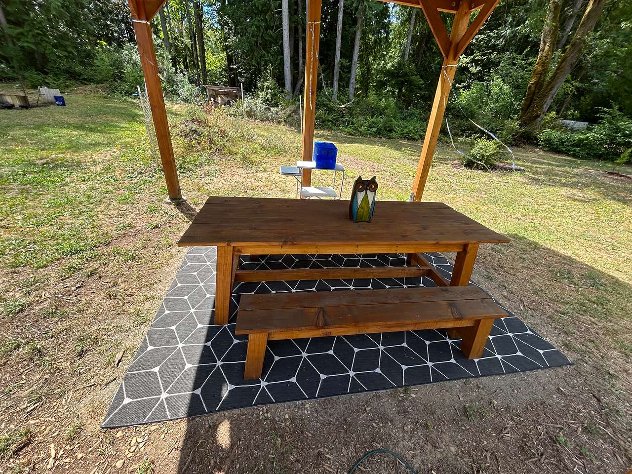 Common area farm table made with wood from the property provides a covered dining space for all guests to dine and hangout near the fire.